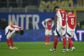 Football players from a team in red and white jerseys showing expressions of disappointment on the field after a match.
