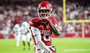 A football player in a red uniform celebrates after a successful play on the field.